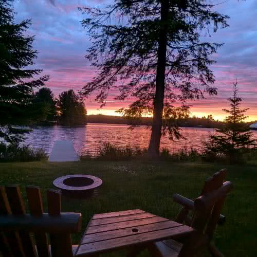 Zona de barbacoa y comedor al aire libre en Smile Awhile, ideal para barbacoas de verano y comidas familiares rodeadas de naturaleza y altos pinos.